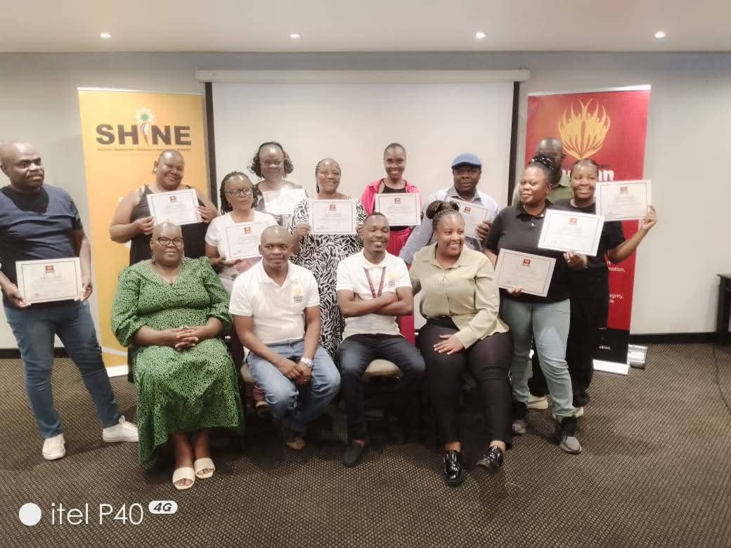 Workshop participants holding certificates at a SHINE training session